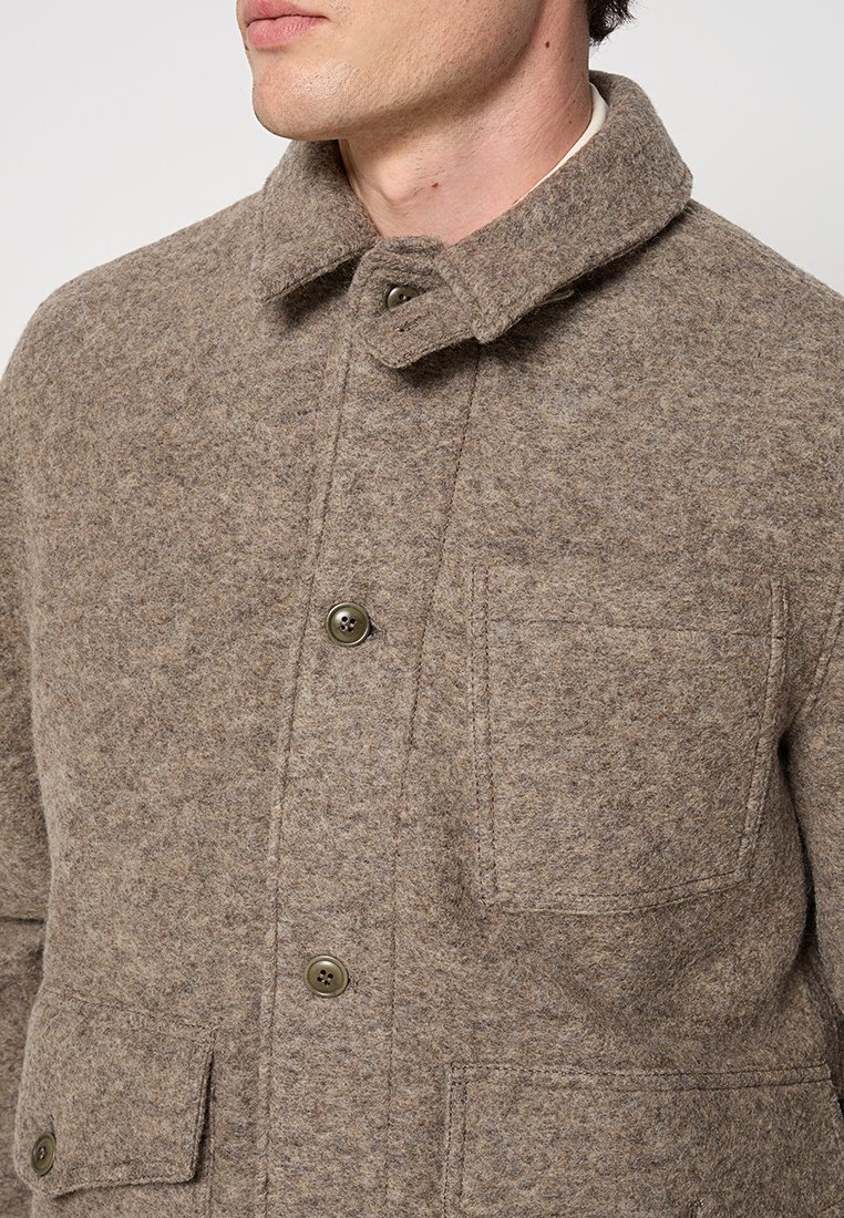 Brauner Wollmantel mit Kragen, Knopfverschluss und zwei vorderen Taschen. Strukturierter Stoff mit einem dezenten Muster für Wärme und Komfort.