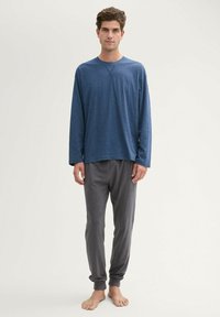 Chemise bleue à manches longues avec col rond et pantalon de jogging gris. Les deux sont en tissu doux et respirant. Coupe ample, design épuré, détails minimalistes.
