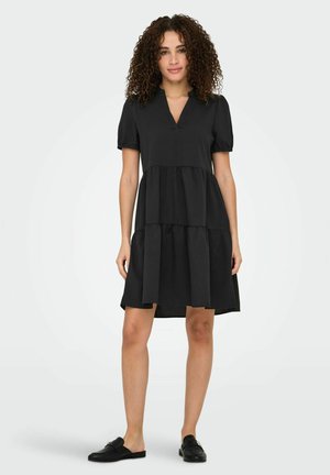 Robe noire longueur genoux avec un design en couches, manches courtes bouffantes et décolleté en V. Fabriquée en tissu doux avec une texture lisse.