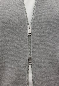 Γκρι φούτερ με φερμουάρ και υφή πλέξης, διαθέτει διπλά φερμουάρ και έχει λε�υκή εσωτερική επένδυση.