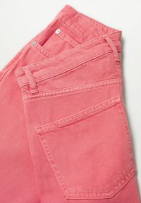 Jean denim rose avec une finition texturée, comprenant des poches standard et des passants pour ceinture. Le tissu est légèrement délavé, mettant en valeur les détails de la couture.