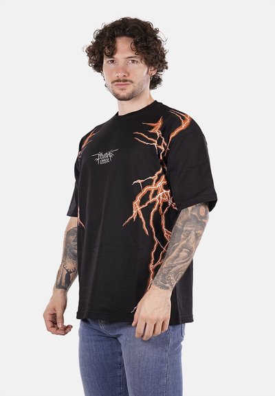 T-shirt nera in cotone con design di fulmini arancioni sul fronte e sul lato. Maniche corte, colletto rotondo, vestibilità rilassata e orlo pulito.
