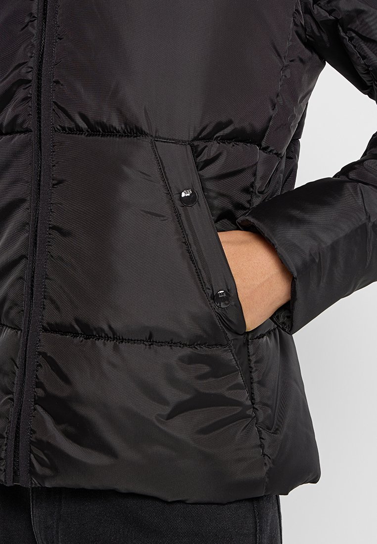 Chaqueta de plumas negra con un acabado brillante, que cuenta con un cierre de cremallera y dos bolsillos laterales con botones a presión. Textura acolchada y mangas ajustadas.