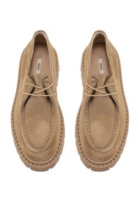 Beige Wildlederschlüpfschuhe mit runder Zehenform und vorderem Schnürverschluss. Sie verfügen über eine dicke, strukturierte Gummisohle mit einer Naht entlang der Kante.