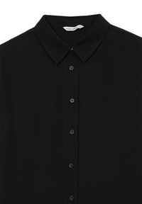 Chemise noire à boutons, col pointu, manches longues et étiquette de marque visible « Calliope » sur l'étiquette intérieure du col.