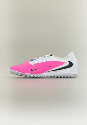 Chaussure de sport blanche et rose avec logos Nike swoosh noirs et semelle texturée conçue pour les sports sur gazon.