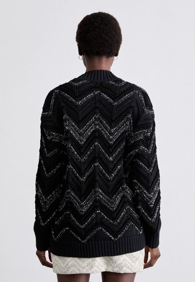 Μαύρο πλεκτό πουλόβερ με σχέδιο ζιγκ-ζαγκ και ασημί λεπτομέρειες, ριχτές μανσέτες και τελείωμα, και στρογγυλή λαιμόκοψη. Υφή και παχιά εμφάνιση.