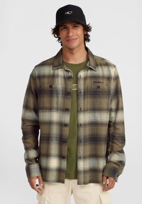 Button-up flannel shirt in shades of green, cream, and black plaid. Features a black logo on the left chest and a collared design.