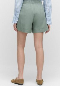 Ljusgröna linnebyxor med en avslappnad passform, med resårmidja och muddar, styler med en blå randig långärmad skjorta.