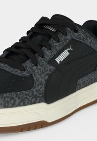Μαύρο και γκρι αθλητικό παπούτσι Puma με σχέδιο λεοπάρδαλης, μαύρα κορδόνια, λευκό λογότυπο Puma και λευκή σόλα με καφέ πάτο.