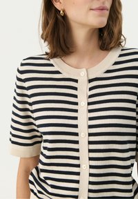Striped cardigan in cream and navy, featuring short sleeves, a round neckline, and five buttons down the front. Smooth knit texture.