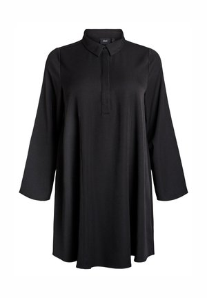 Melnu tuniku ar garām piedurknēm, punktētu apkakli un slēptu pogu plātni, brīvu piegriezumu un līdz vidusceļam garumu.