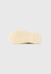 Σόλα αθλητικού παπουτσιού εκρού με λεπτομερή σχέδια πέλματος εμφανίζεται σε απλό λευκό φόντο.