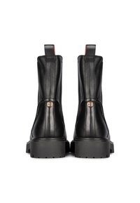 Botas de tobillo de cuero negro con un acabado texturizado, tacón reforzado y suela de goma gruesa, con acentos rojos y herrajes en tono dorado.