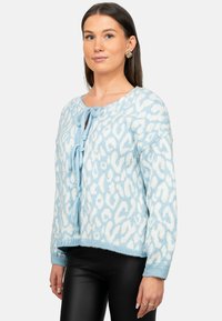 Cardigan lavorato a maglia blu chiaro con una texture morbida e pelosa, motivo a stampa leopardata e chiusura con fiocco frontale. Maniche lunghe e scollatura rotonda.