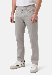 Graue Hose im Slim-Fit-Design mit strukturierter Stoffqualität. Mit Knopfverschluss, fünf Taschen und kombiniert mit weißen Sneakers.