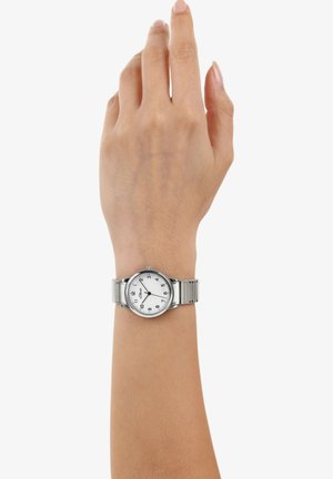 Silberner Edelstahl-Armbanduhr mit einem runden weißen Zifferblatt, schwarzen Ziffern und einem Metallarmband, getragen an einer Hand mit einem neutralen Hautton.