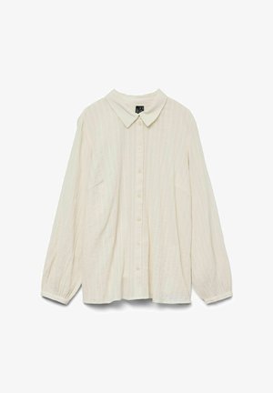 Kreminės spalvos marškinėliai su apykakle, ilgomis rankovėmis ir vertikaliomis juostelėmis. Yra mygtukų uždarymas ir laisvas fasonas, pagaminti iš tekstūrinio audinio.