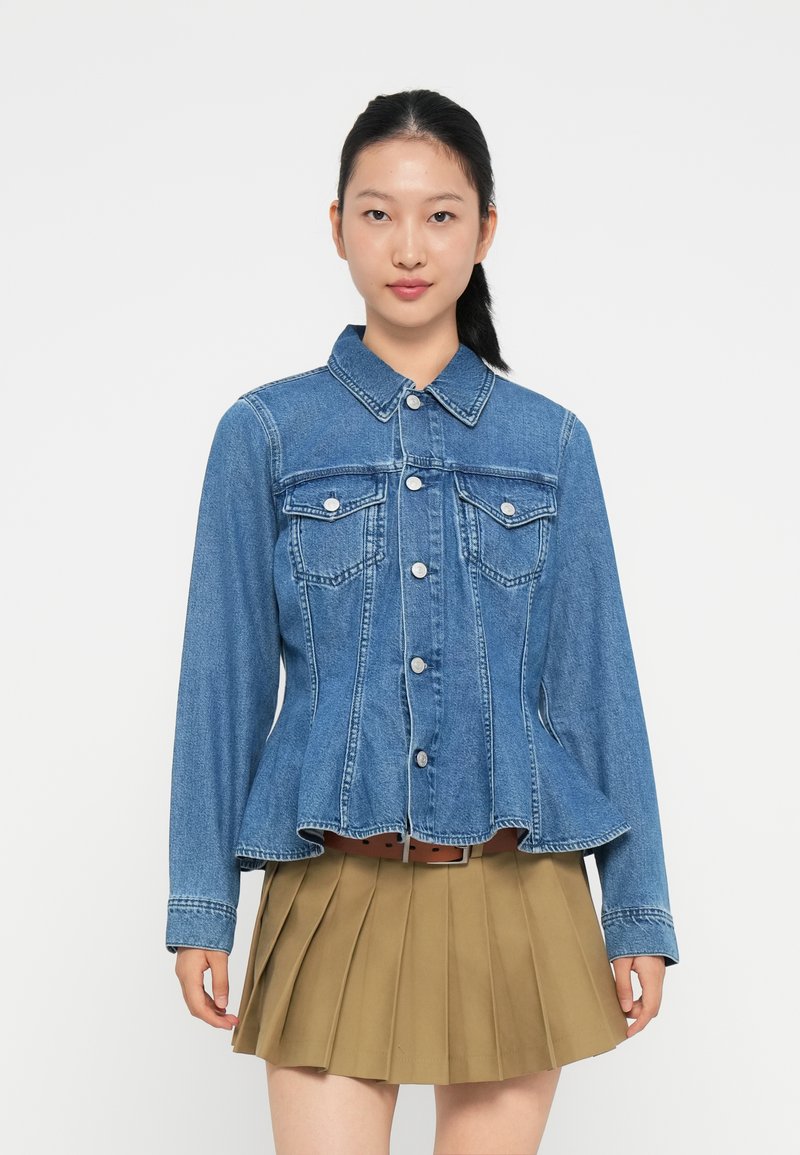 Jeansjakken har en knappestengt front, to brystlommer og en peplum-fall. Den har en lys blå farge med kontrasterende sømmer.