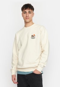Crème-kleurige sweatshirt van katoen, met een "Outdoor Therapy" logo met bergen en een zon. Lange mouwen met ribbelmanchetten.
