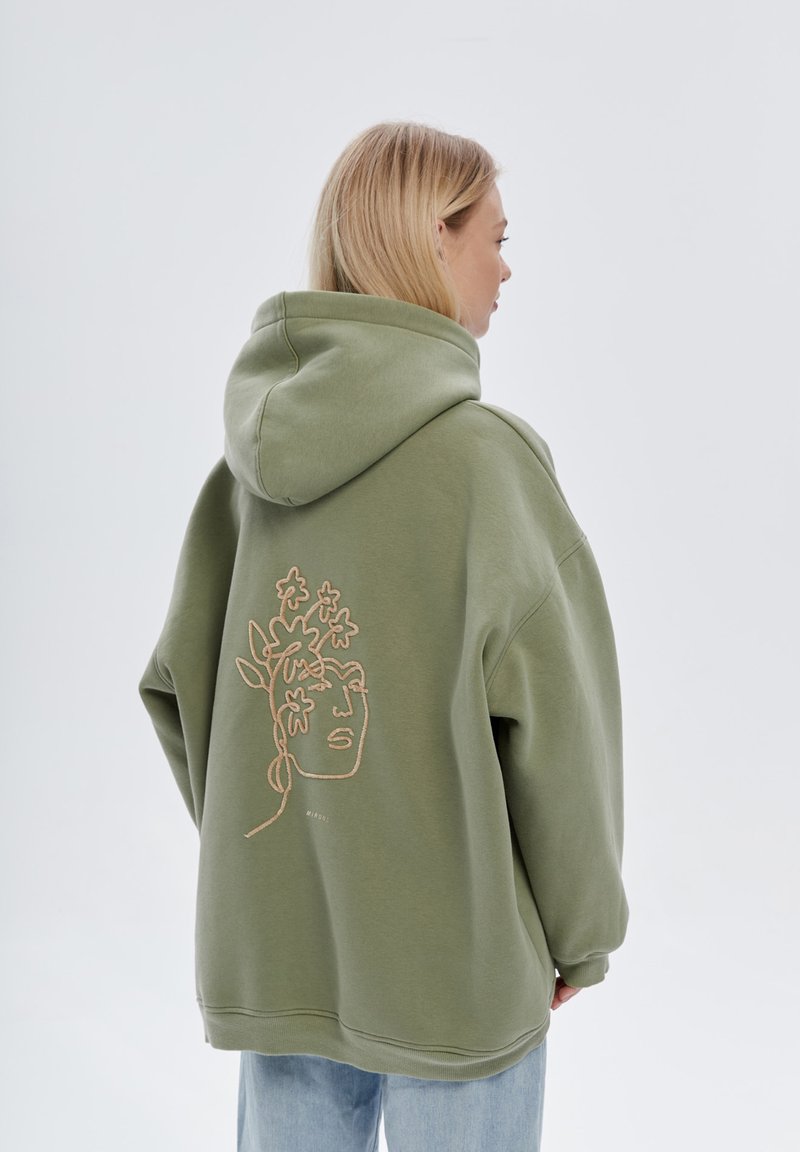 Felpa oversized verde oliva con cappuccio, caratterizzata da un design floreale ricamato color beige sulla schiena e polsini a costine.