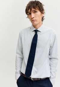 Valge ja helesinise triibuline nööpidega särk, millele on lisatud üksvärviline mereväe lips. Oman pikad varrukad ja krae. Must vöö hõbedase pandlaga.