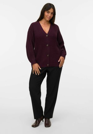 Cárdigan de punto en color púrpura oscuro con escote en V y mangas largas, con cinco botones marrones y un ajuste relajado, combinado con pantalones negros y botas marrones.