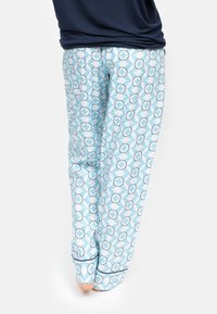 Pantalons de pyjama bleu clair présentant un motif géométrique de cercles superposés. Tissu doux avec une coupe décontractée et des chevilles resserrées.