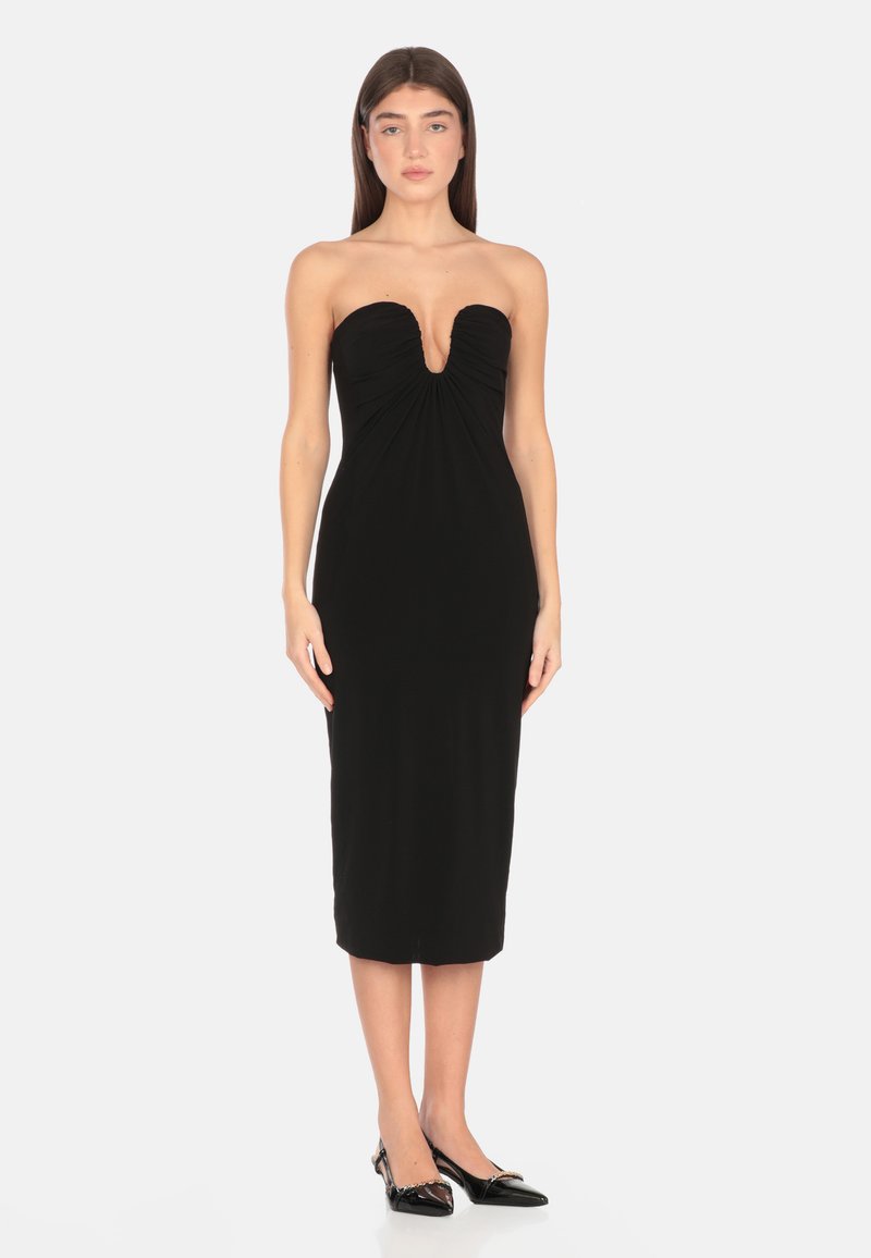 Abito midi nero senza spalline con tessuto arricciato e scollatura a V profonda. Texture liscia e silhouette aderente, abbinato a tacchi neri a punta.