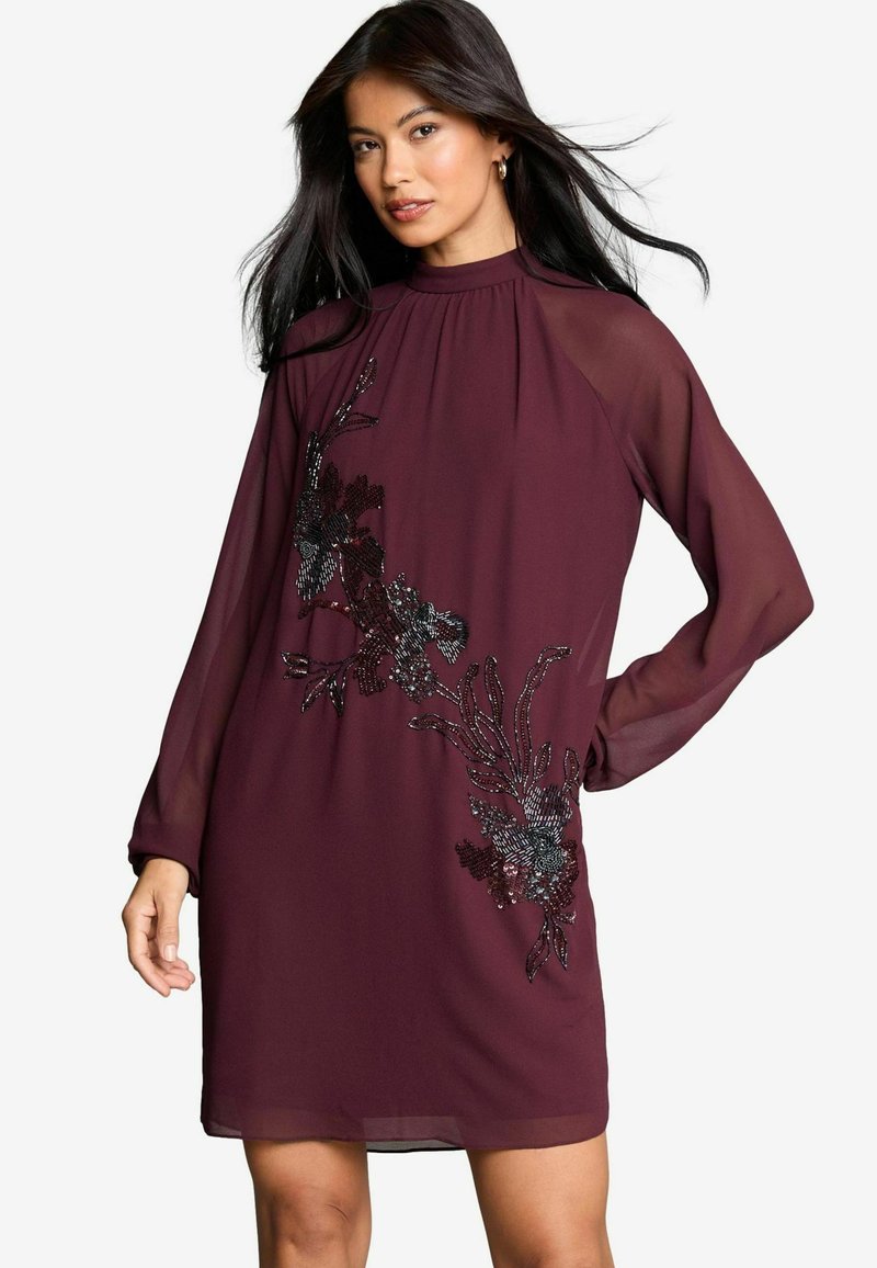 Vestido burdeos con mangas largas y transparentes, escote alto y adornos de cuentas florales en un lado. Tejido ligero, diseño a la altura de la rodilla.
