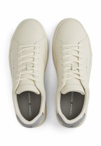 Sneaker color crema realizzate in pelle liscia con punta rotonda, lacci piatti e un accento sul tallone grigio. Marchio visibile sul lato.