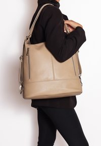 Borsa a tracolla in pelle beige con una finitura testurizzata, dotata di due cerniere laterali, un corpo ampio e una lunga tracolla regolabile per indossarla crossbody.