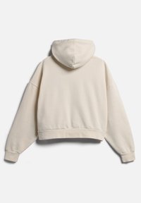 Kaptuell krämfärgad hoodie med dragsko i huvan, rymliga långa ärmar och en mjuk textur. Har en ribbad nederkant och ärmmuddar.