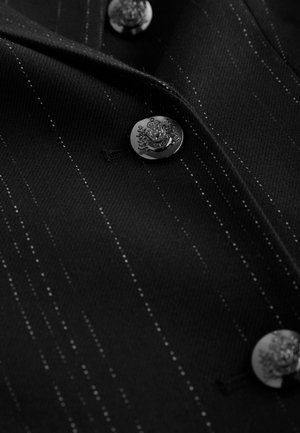 Black fabric with white pinstripes, featuring metallic buttons with ornate detailing. Smooth texture, tailored design, and structured collar.