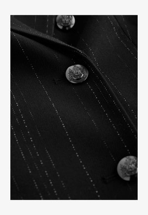Black fabric with white pinstripes, featuring metallic buttons with ornate detailing. Smooth texture, tailored design, and structured collar.