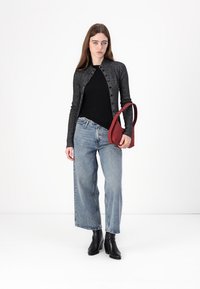 Svart langermet topp under en grå cardigan, kombinert med lyseblå vide jeans og svarte hæl ankelsko. En rød skulderveske er inkludert.