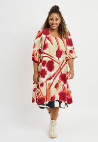 Bunt gemustertes knielanges Kleid mit floralen Motiven in Rot- und Rosatönen, kurzen Puffärmeln und einem Rundhalsausschnitt.