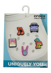 Fargerike gummidekorasjoner for Crocs inkluderer en lilla varebil, note, landskap, skjeletthånd og sopper, vist på en hvit sko.