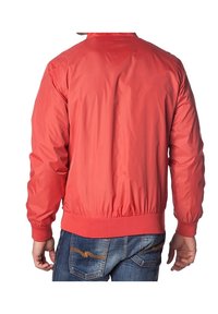 Veste bomber rouge avec une texture lisse et brillante, des poignets et un ourlet côtelés, et un col montant, portée sur un jean bleu.