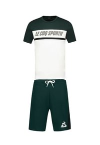 Camiseta con un top verde, centro blanco y una franja negra con el texto "LE COQ SPORTIF"; combinada con pantalones cortos verde oscuro con cordón.