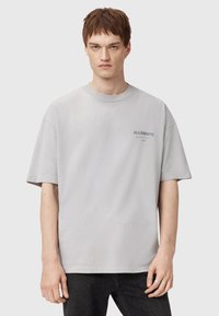 T-shirt oversize gris clair en coton. Doté d'un col rond et de manches courtes, avec un petit logo imprimé sur le devant.