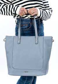 Sac à main tote en cuir bleu clair avec une surface texturée, deux poignées robustes et des accents métalliques sur les côtés. Convient pour un usage quotidien.