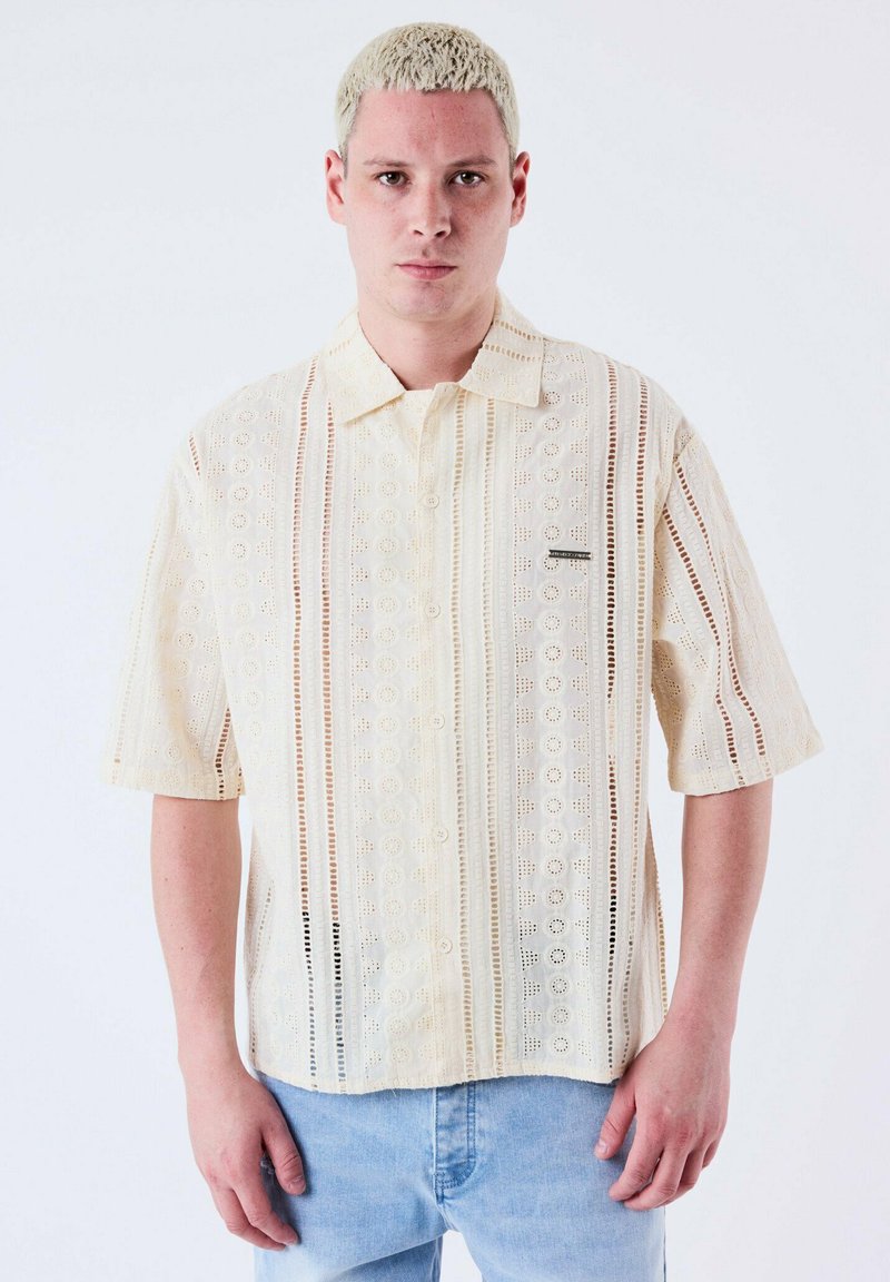 Korte mouwen, crèmekleurig shirt met een patroonstructuur, voorzien van knoopsluiting en dunne strepen. Gemaakt van lichtgewicht stof.
