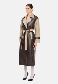 Bruin- en beige color-block trenchcoat met een tailleband, gemaakt van een glad, leerachtig materiaal; voorzien van grote revers en knoopdetails.