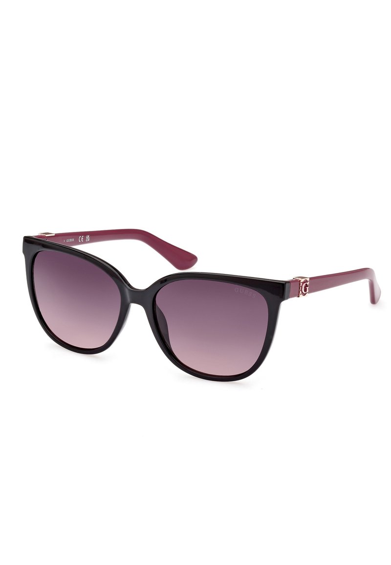 Lunettes de soleil à œil de chat avec monture noire et verres dégradés violets. Les branches bordeaux présentent un accent logo en argent. Matériau plastique lisse, design léger.