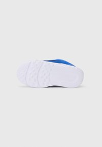 Chaussure de sport bleue avec une semelle en caoutchouc blanc texturé. Présente un design supérieur lisse avec des coutures minimales et un ajustement serré.