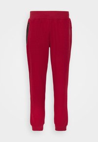 Rote Baumwoll-Sweatpants mit schmal zulaufenden Knöcheln, elastischem Bund und zwei seitlichen Taschen mit schwarzen Reißverschlüssen. Glatte Textur, lässiges Design.