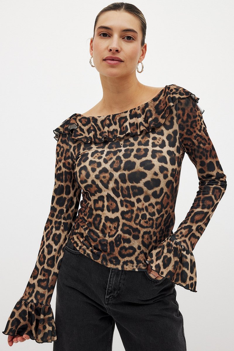 Leopard-print top with ruffled neckline and flared sleeves, made from a smooth fabric in brown and black tones, paired with dark jeans.