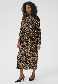 Abito a maniche lunghe con stampa leopardata in beige e nero, caratterizzato da una chiusura con bottoni davanti, una cintura in vita e una lunghezza midi dritta.