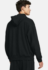 Musta huppari ribbitekstuurilla, rento malli, pudotetut hihat sekä joustavat hihansuut ja helma. Takakuvassa näkyy huppuyksityiskohta.